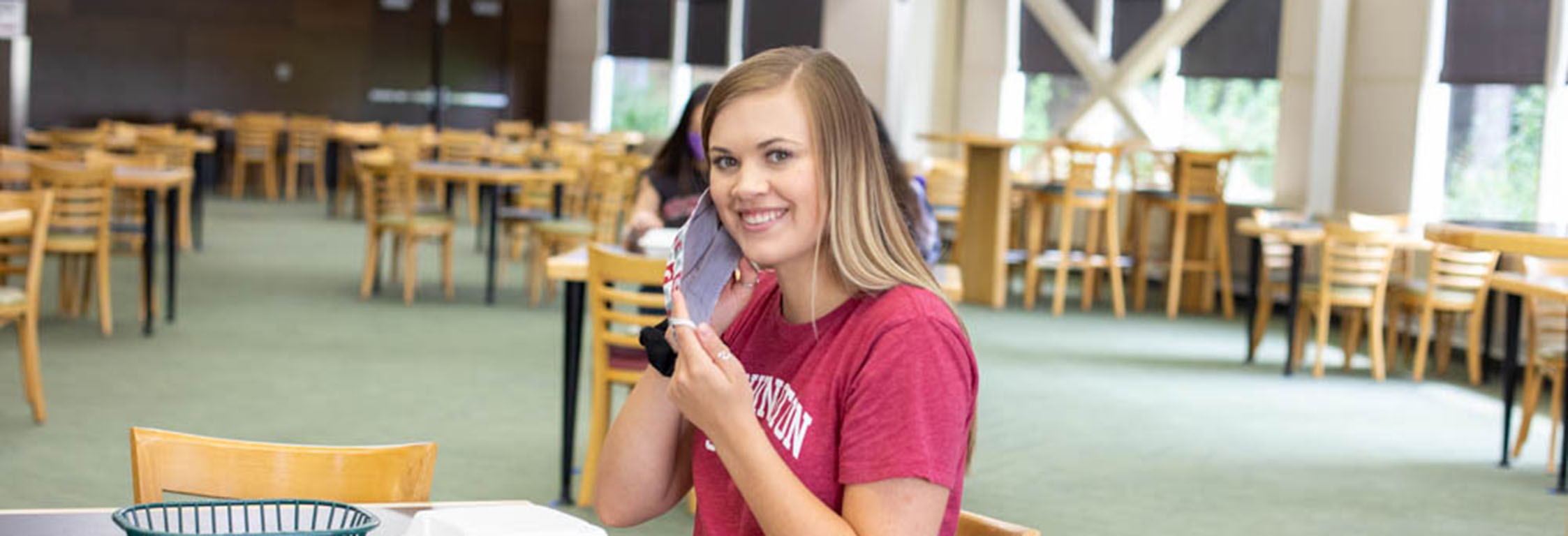 A student sits down to eat at Southside Cafe and takes off their mask.